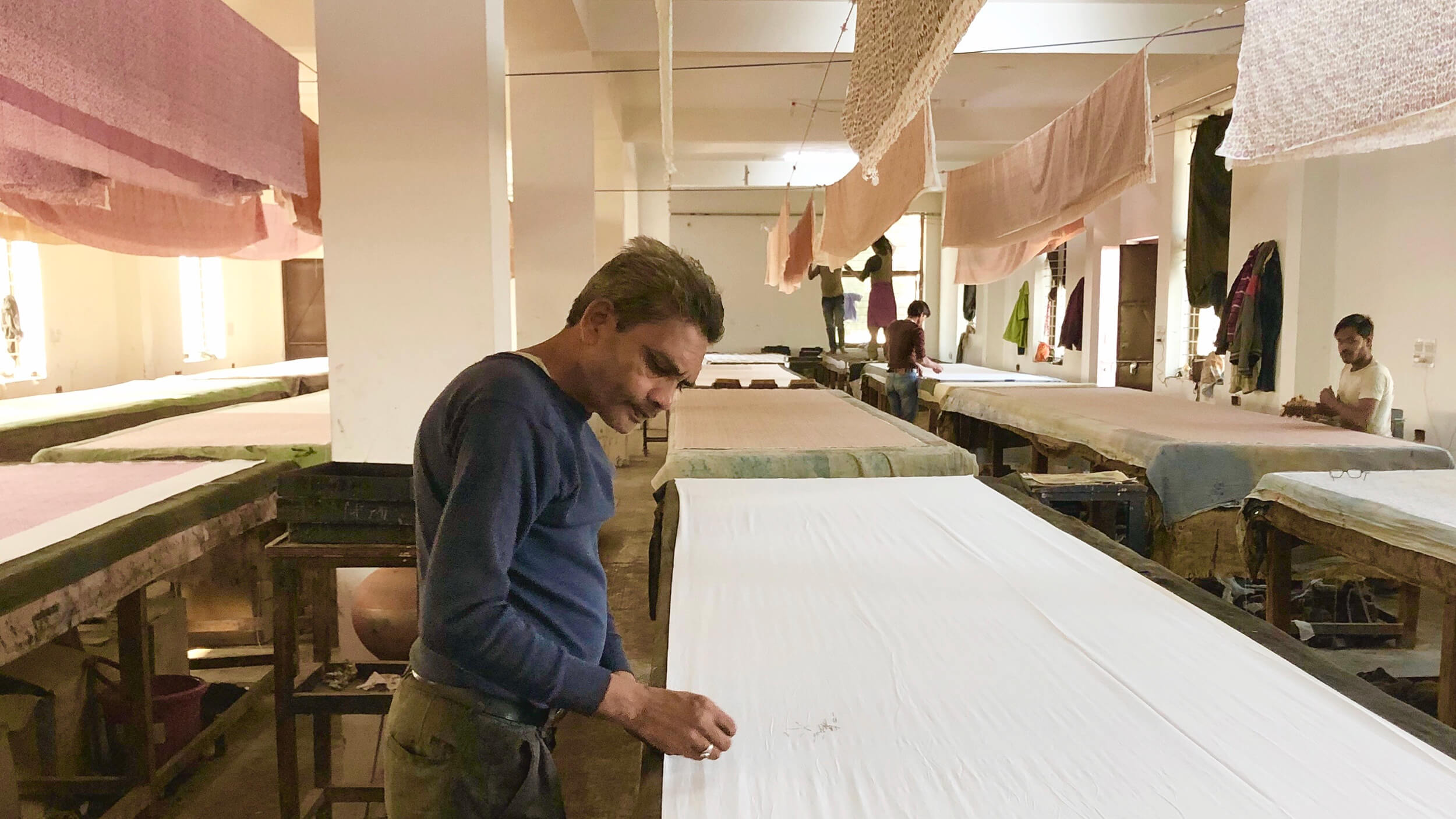 広い木版工房で作業台に布を張る木版プリント職人